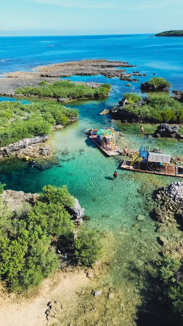 An aerial view of the turquoise tidal rock pools and bamboo rafts at Immuki Island in Balaoan.
