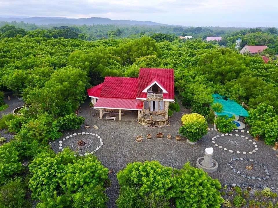 An aerial view of the red-roofed stone art house and garden of Bahay na Bato in Luna.