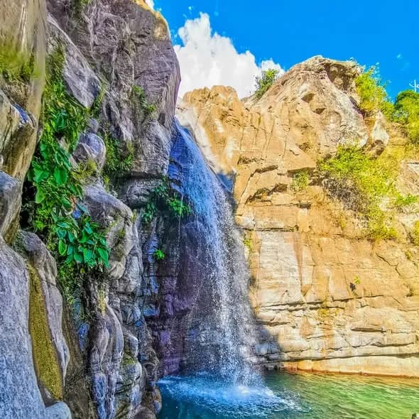 Bulalakaw Falls descending between high rock walls into a turquoise pool in Bagulin