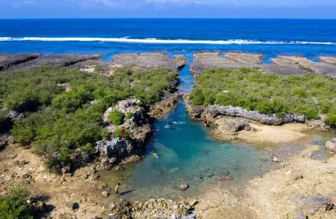 Turquoise rock pools opening toward the sea at Immuki Island in Balaoan