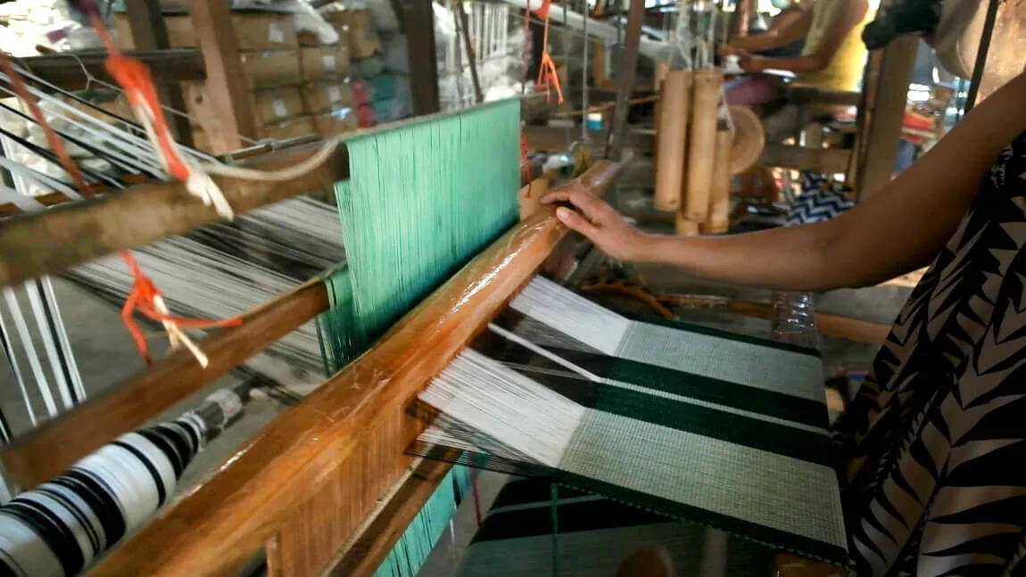A Bangar artisan weaving inabel cloth on a traditional wooden loom